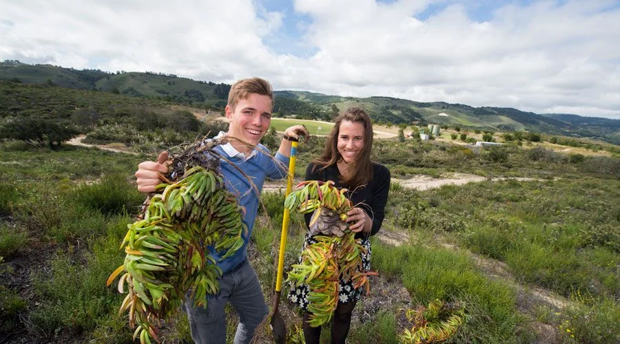 two students holding plants