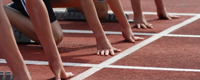 hands of students lined up at track starting line